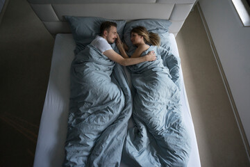 Top view of affectionate couple lying in bed at home