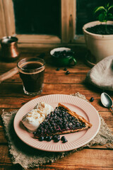 One Slice of Amelanchier Berries Galette and Ice Cream on Plate with Glass of Coffee