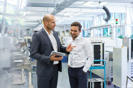 Confident businessman discussing with engineer over digital tablet at factory