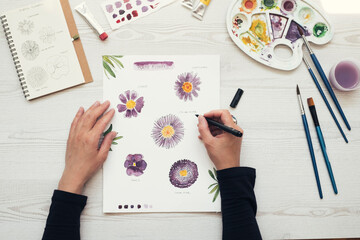 Woman painting flowers with water colors, top view