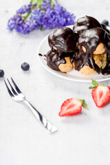Profitrolls decorated with chocolate on a light background. Close up