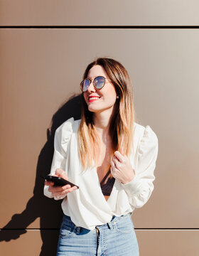 Portrait of smiling young woman with smartphone looking at distance