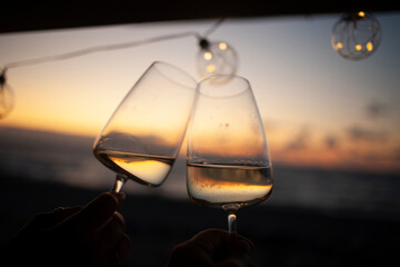 Woman holding two glasses of white wine in van at sunset