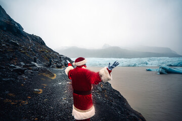Iceland, back view of Santa Claus standing in front of glacier