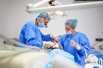 Dental surgeon and assistant work putting dental implant