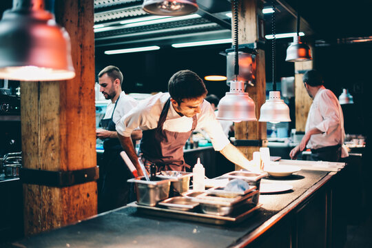 Cook serving food on a plate in the kitchen of a restaurant