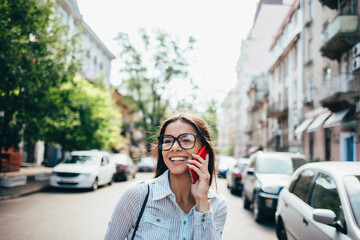 Happy young businesswoman talking on cell phone on the street