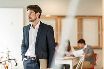 Businessman holding tablet with a meeting in background