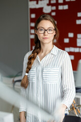Portait of confident young woman in office in front of scrum board