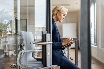 Blond businesswoman using tablet in conference room