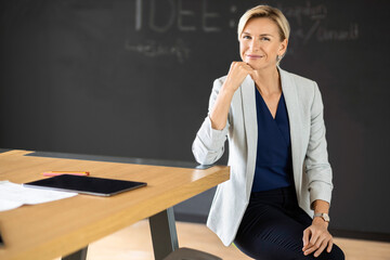 Portrait of confident blond businesswoman in conference room with blackboard