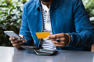 Close-up of man with credit card making mobile payment at sidewalk cafe - obrazy, fototapety, plakaty