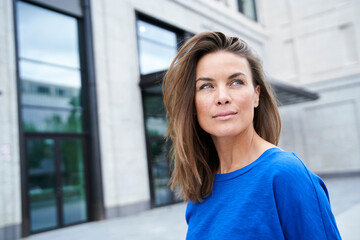 Portrait of attractive brunette woman wearing blue top in the city