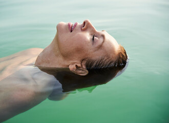 Mature woman floating in a lake with closed eyes
