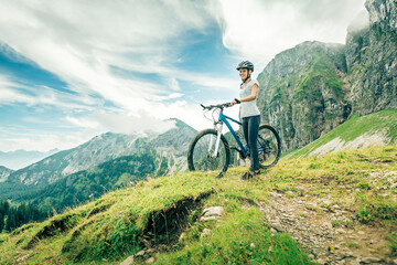 Germany, Bavaria, Pfronten, smiling teenage girl with mountain bike on alpine meadow near Aggenstein