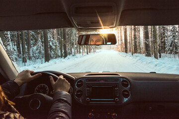 Finland, Kuopio, woman driving car in winter landscape at sunset