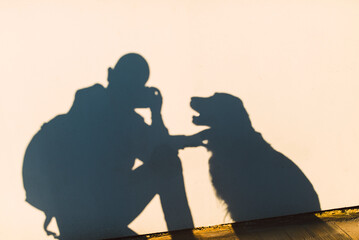 Shadow of a photographer and dog on a white wall