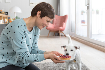 Smiling woman presenting her dog a birthday cake