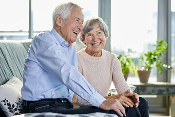 Portrait of laughing senior couple sitting together on couch