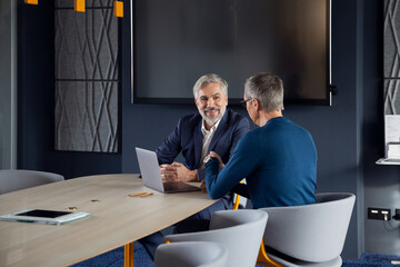 Two smiling businessmen working together on a project in office