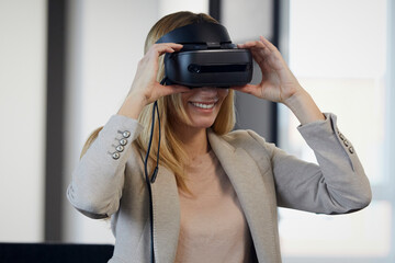 Smiling businesswoman wearing VR glasses in office