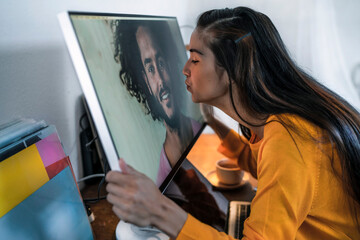 Young woman kissing man on computer screen