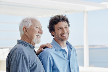 Portrait of confident senior man with adult son at a beach house - obrazy, fototapety, plakaty