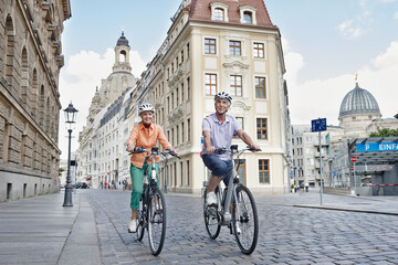 Senior tourists riding electric bicycle against Frauenkirche Cathedral at Dresden, Germany