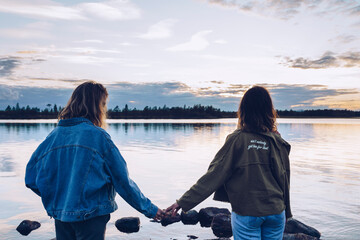 Girl friends looking at Lake Inari,Finland, holding hands
