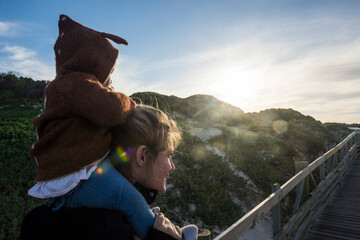 Mother and baby girl, sitting on her shoulders, on the way to Boulders beach