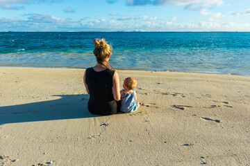 Cook islands, Rarotonga, Woman sitting with her baby on a white sand beach