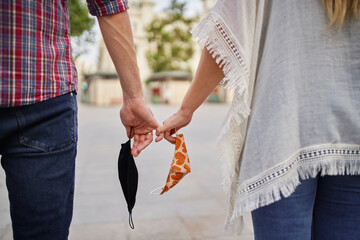 Close-up of couple with face mask holding hand on street in city