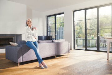 Senior woman standing by couch in living room