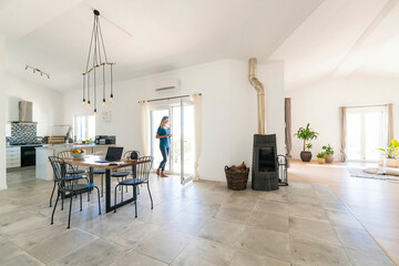Woman standing in door frame of modern living room with fireplace
