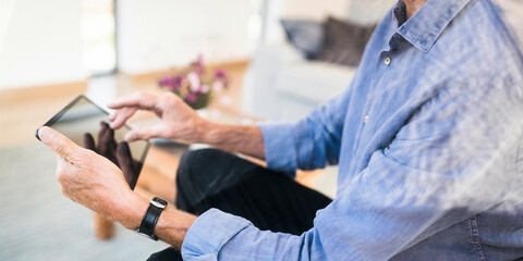 Close-up of senior man using tablet at home