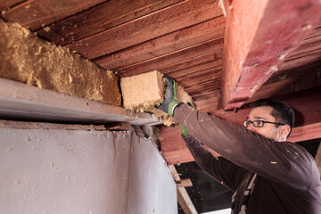 Roof insulation, worker filling pitched roof with wood fibre insulation