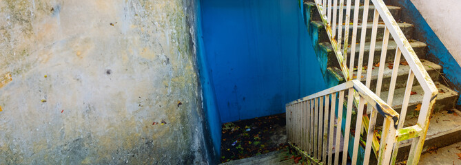 dirty stairs , rusty and filled with junk , blue wall
