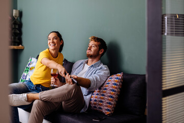 Young couple sitting on the couch at home watching tv