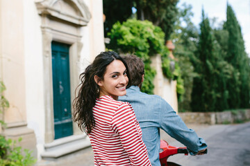 Smiling woman sitting with boyfriend on Vespa