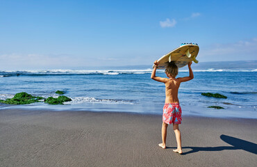 Chile, Pichilemu, boy carrying surfboard at the sea