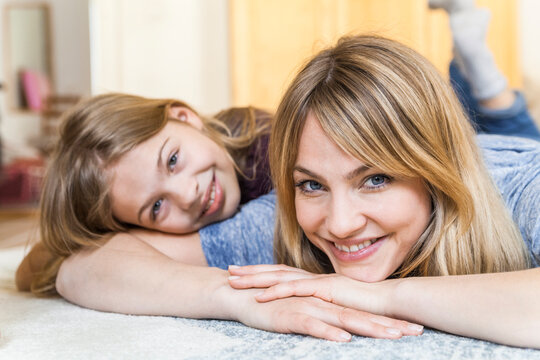 Portrait of smiling blond woman lying on the floor with her daughther