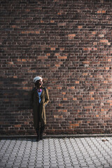 Young woman standing in front of brick wall