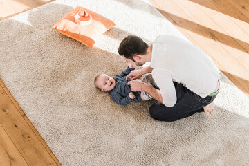 Father changing diapers and playing with his baby son