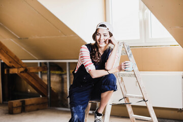 Young woman on construction site of her new home, holding