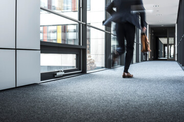 Businessman running in corridor of an office building - Powered by Adobe