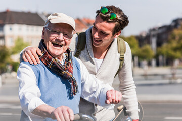 Happy senior man with adult grandson in the city on the move