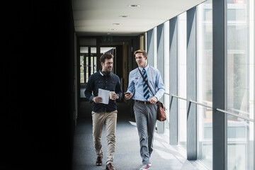 Two colleagues walking and talking on office floor
