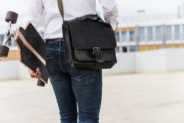 Businessman with and skateboard walking at parking garage