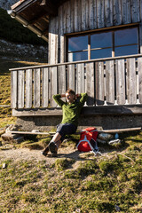 Mature man relaxing at a mountain hut, enjoying the sun