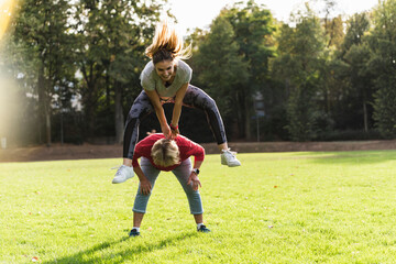 Granddaughter leapfrogging over her grandmother in a park